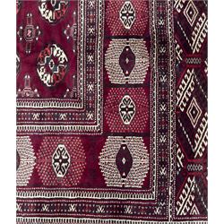 Northeastern Persian Yamut  hand-knotted carpet, the rich burgundy field with repeating rows of stepped gul motifs in cream and black, enclosed by multiple linear and geometric borders with hooked motifs and diamond medallions