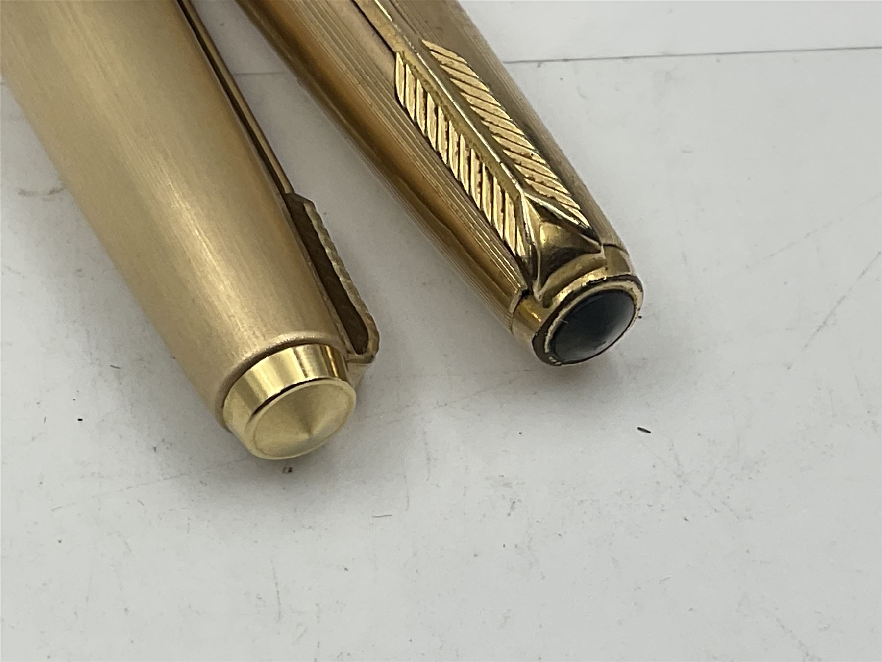 Three rolled gold Parker fountain pens, comprising an example with a gold nib marked 14K 585 and barrel with a shell stamp, a Parker 61 fountain pen with inset gold arrow to the nib, and another similar, all with striated decoration and arrow clips to the caps, L13cm, one with box