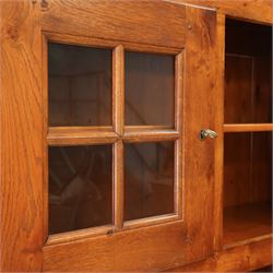 Traditional design solid oak dresser, moulded cornice over twin glazed doors enclosing shelved interior, open centre section, lower base with fielded panel doors opening to shelved cupboards, on plinth base
