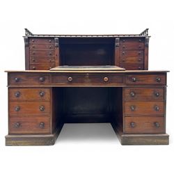 Large Victorian mahogany Registry/Dickens’ desk, spindle gallery top, one side with five small drawers and the other with blind cupboard drawer, revealing pigeon holes with scroll carved locking side bars on either side, above a hinged and leathered writing slope with three drawers and pigeon holes underneath, above a central locking drawer with key, the pedestals each with four drawers and  turned knob handles, separates into four parts for transport