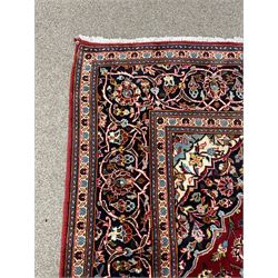 Persian Kashan rug, red ground and decorated with stylised flower heads, central blue ground medallion and matching spandrels, scrolling design guarded border