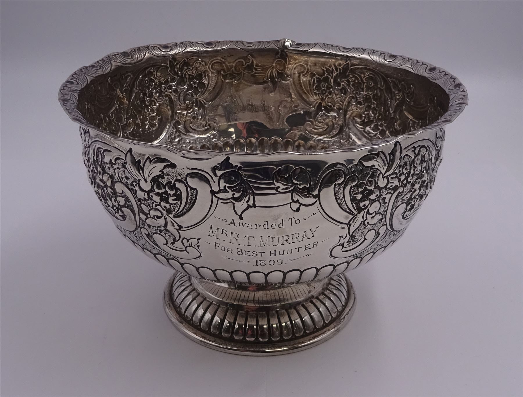 Late Victorian silver rose bowl, of circular form with embossed foliate and C scroll decoration, and engraved personal dedication, upon a part fluted spreading circular foot, hallmarked Wakely & Wheeler, London 1898, H11.5cm D18cm, approximate weight 11.67 ozt (363.2 grams)