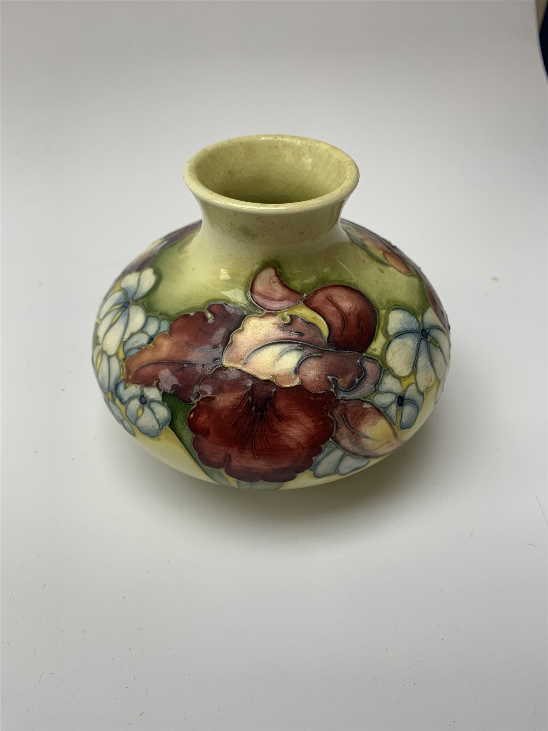 A Moorcroft vase, circa 1950, of squat bulbous form, decorated in the Orchid pattern upon a yellow glazed ground, with impressed and blue painted WM initials for Walter Moorcroft, H10.5cm. 