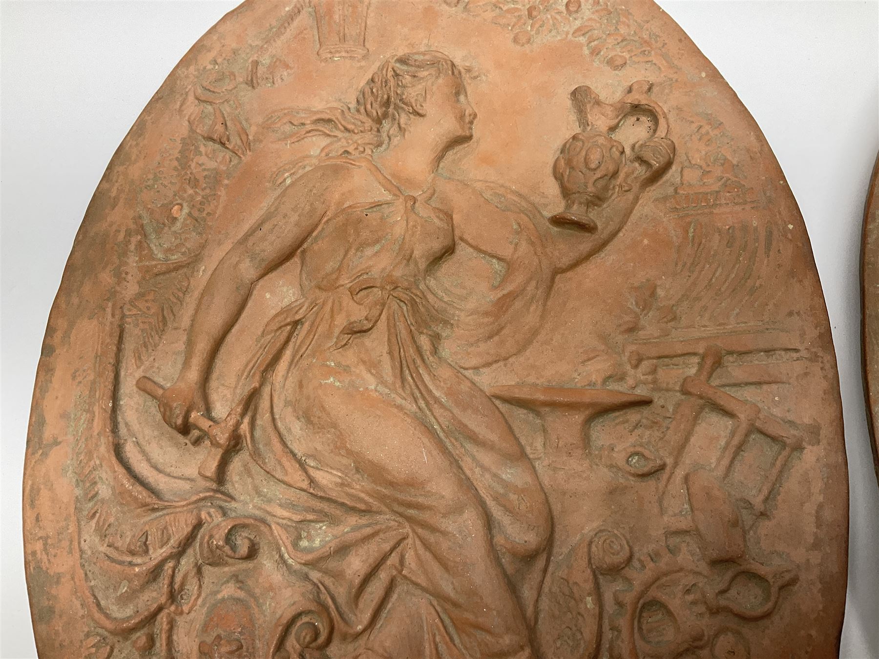 Pair of 19th century classical terracotta relief wall plaques depicting the goddess Hygeia and another goddess, seated holding an ewer, each of oval form, indistinctly signed, each stamped Ferreira verso, H42cm, W30cm