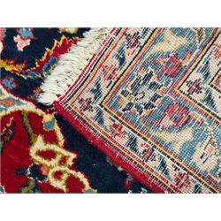 Persian Kashan crimson ground carpet, the central pole medallion decorated with flower heads, surrounded by trailing leafy branches and palmettes, scrolling border decorated with further palmettes, within floral pattern guard stripes 