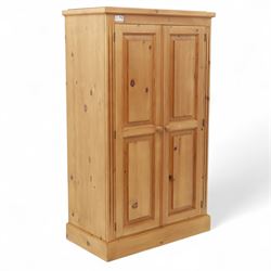 Modern stripped pine two-door wardrobe, the fielded panel doors with turned knob handles, opening to a double rail hanging interior, beneath a stepped cornice and raised on plinth base