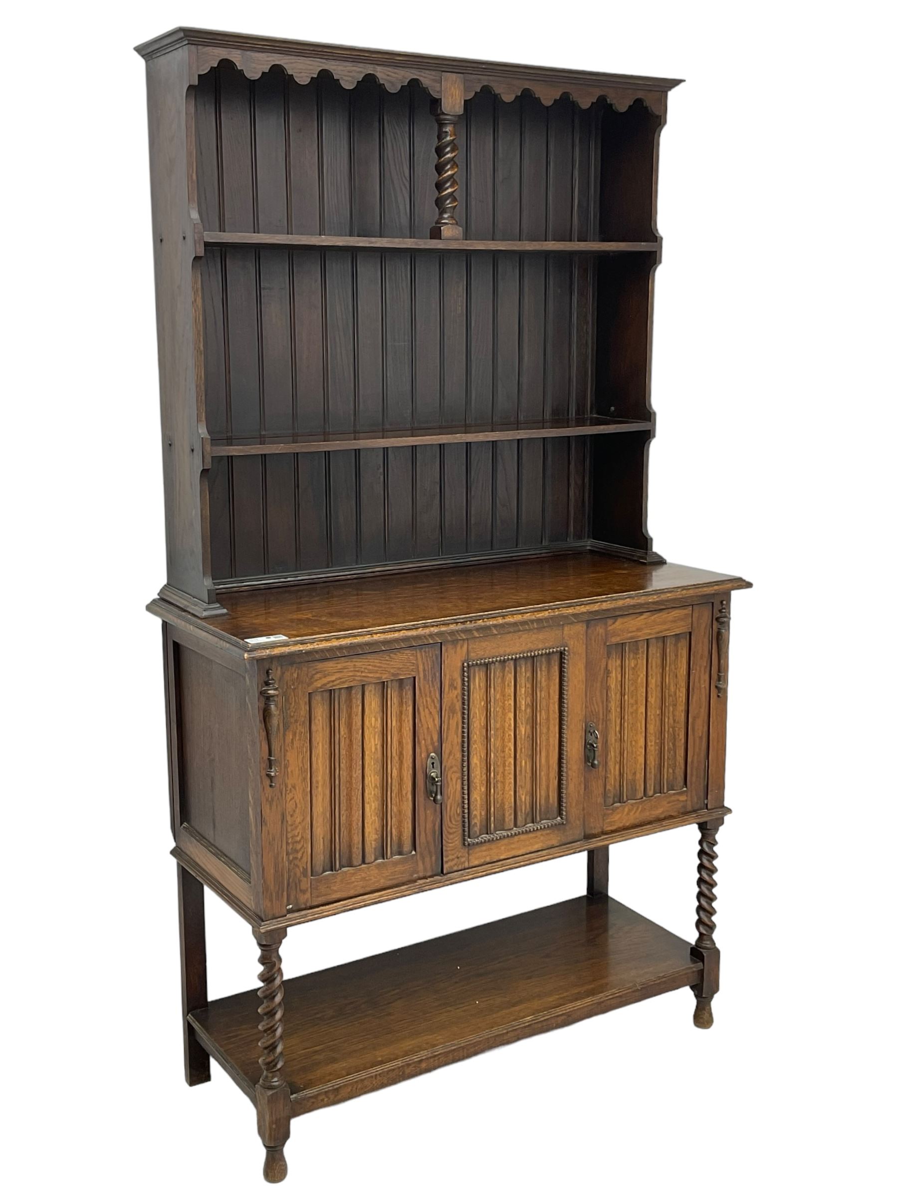 Early to mid-20th century oak dresser, raised two tier plate tack over two linenfold panelled doors, on spiral turned supports united by undertier 