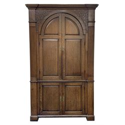 Large George III oak corner cupboard, projecting cornice over two stepped arch doors with fielded panels and blind fret work spandrels, flanked by fluted uprights, cupboard below enclosed by two fielded panel doors, the painted interior fitted with shaped shelves
 