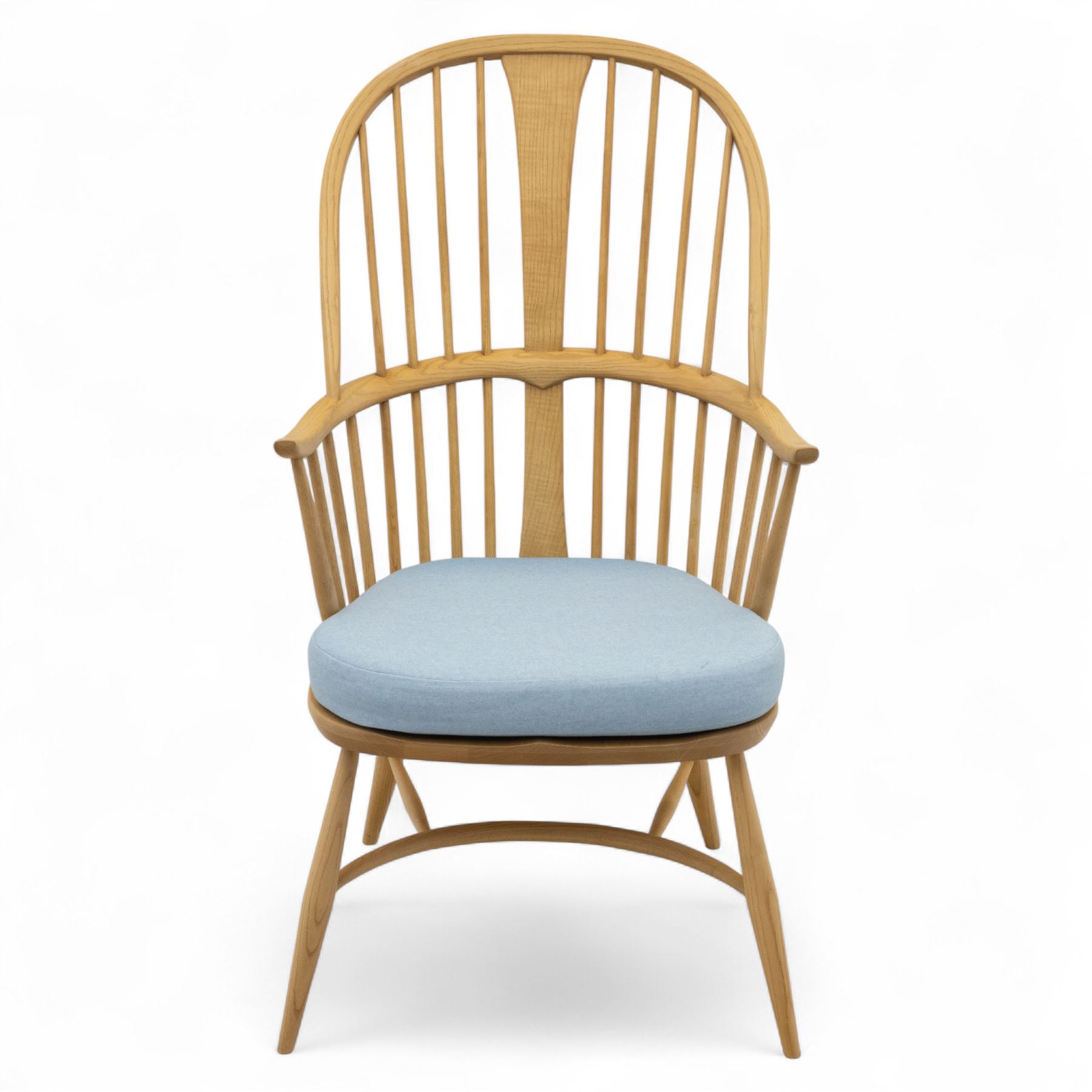 Ercol - ‘Chairmakers’ armchair, of traditional Windsor form in light ash, featuring a hoop back with four spindles and central splat, curved arms and turned supports, dished seat with upholstered blue cushion