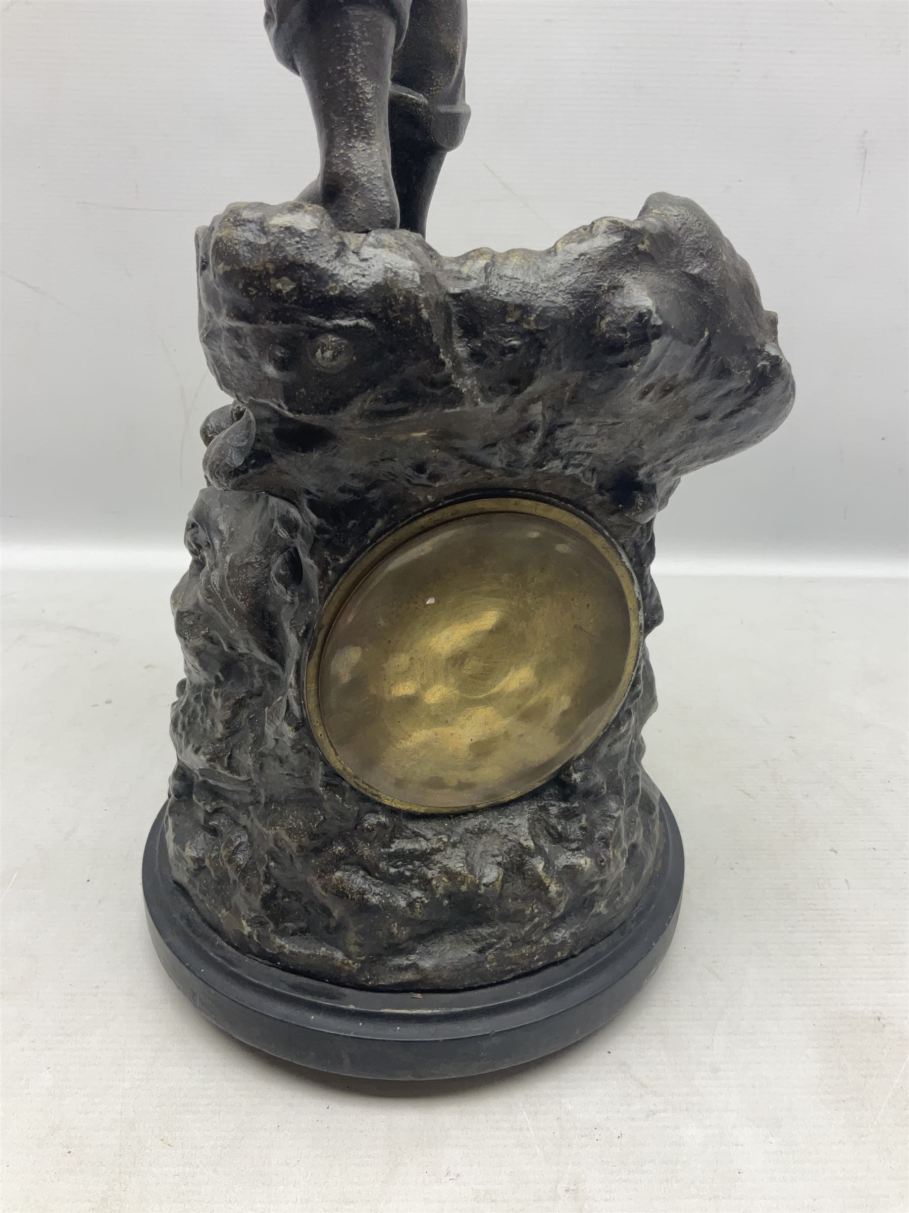 Early 20th century spelter effect figure of a sailor standing in the bow of a boat scanning the horizon, on a simulated rock base with a plaque entitled 'Rescue', base fitted with a timepiece clock movement and two-part dial, with pierced hands, gilt dial centre and ivorene chapter ring written in Arabic numerals, German HAC spring driven going barrel movement wound from the front; with pendulum H65.5cm
