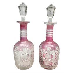 Pair of late 19th/early 20th century cranberry flash cut glass decanters, the bodies with Prussian shoulder with cross hatching, hobstar and hobnail decoration, four band necks, star cut bases and faceted stoppers, H30cm