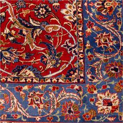 Central Persian Markazi Mahal hand-knotted carpet, terracotta red field, with an all-over scrolling vine design issuing with palmettes, rosettes, and serrated leaves, linked by ivory vinery, deep cobalt blue main border with floral ornamentation, flanked  by multiple guard stripes of repeating geometric motifs, with cotton fringe ends