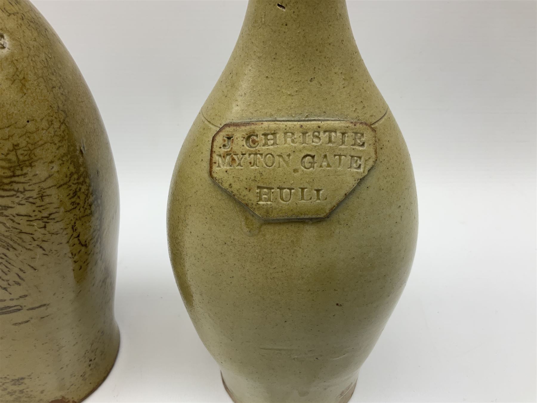  19th century salt glazed stoneware gin bottle impressed John Shaw, Red Lion Vaults, Whitefriargate, Hull of bulbous oval form H27cm and another with impressed label for J. Christie Mytongate Hull (2)  