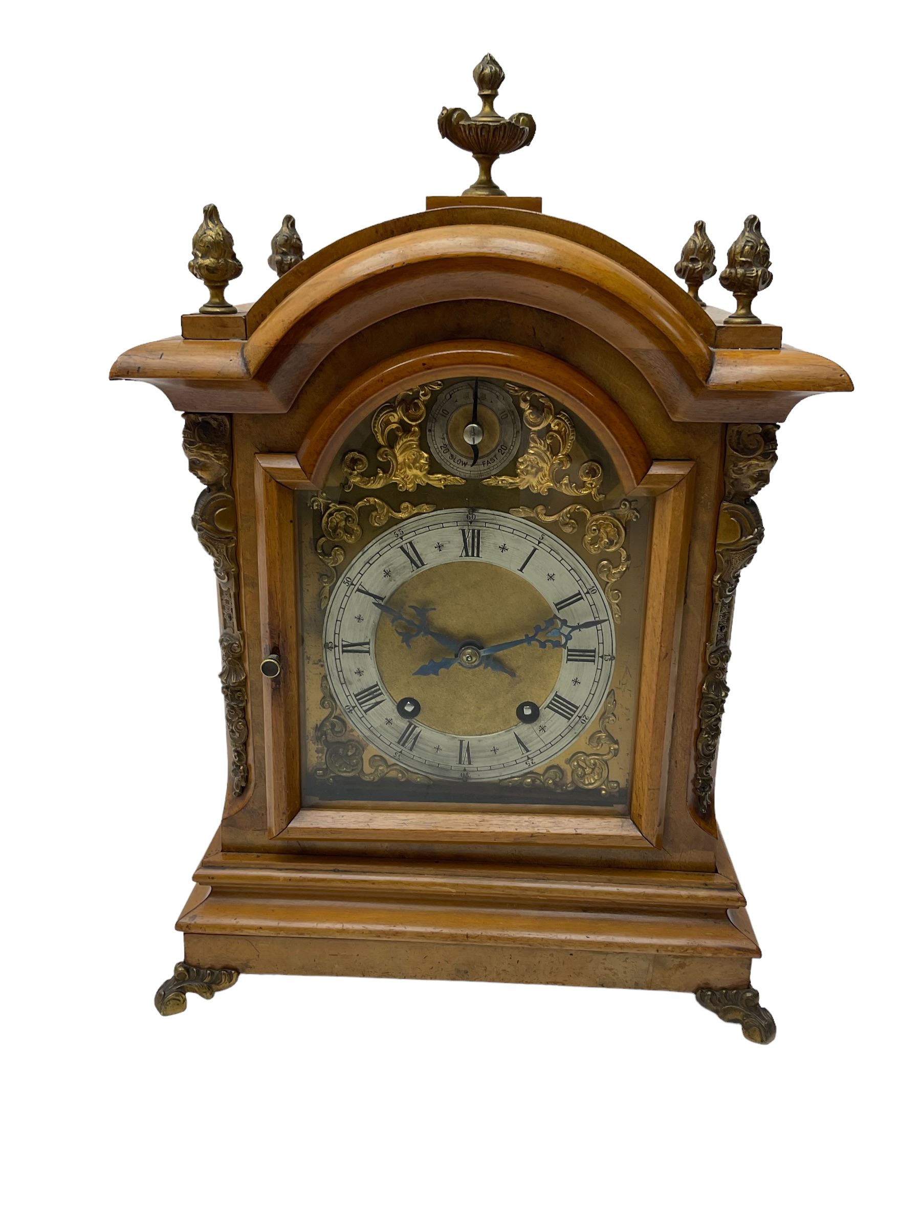 German - 19th century 8-day walnut bracket clock, striking the quarters on two coiled gongs, case with a break-arch top surmounted by cast brass finials, canted corners to the front with cast brass caryatids and sound frets to the sides, brass break arch dial with a silvered chapter ring, steel gothic hands, spandrels, and pendulum regulation dial. With pendulum.