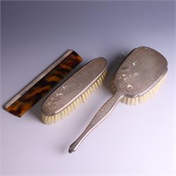 20th Century silver mounted dressing table set, comprising hand mirror, clothes brush, hairbrush and comb holder, each with engine turned and engraved floral decoration, three pieces hallmarked Adie Brothers Ltd Birmingham 1964, the comb holder hallmarked Elkington & Co Ltd Birmingham 1965, contained within a fitted tooled leather case