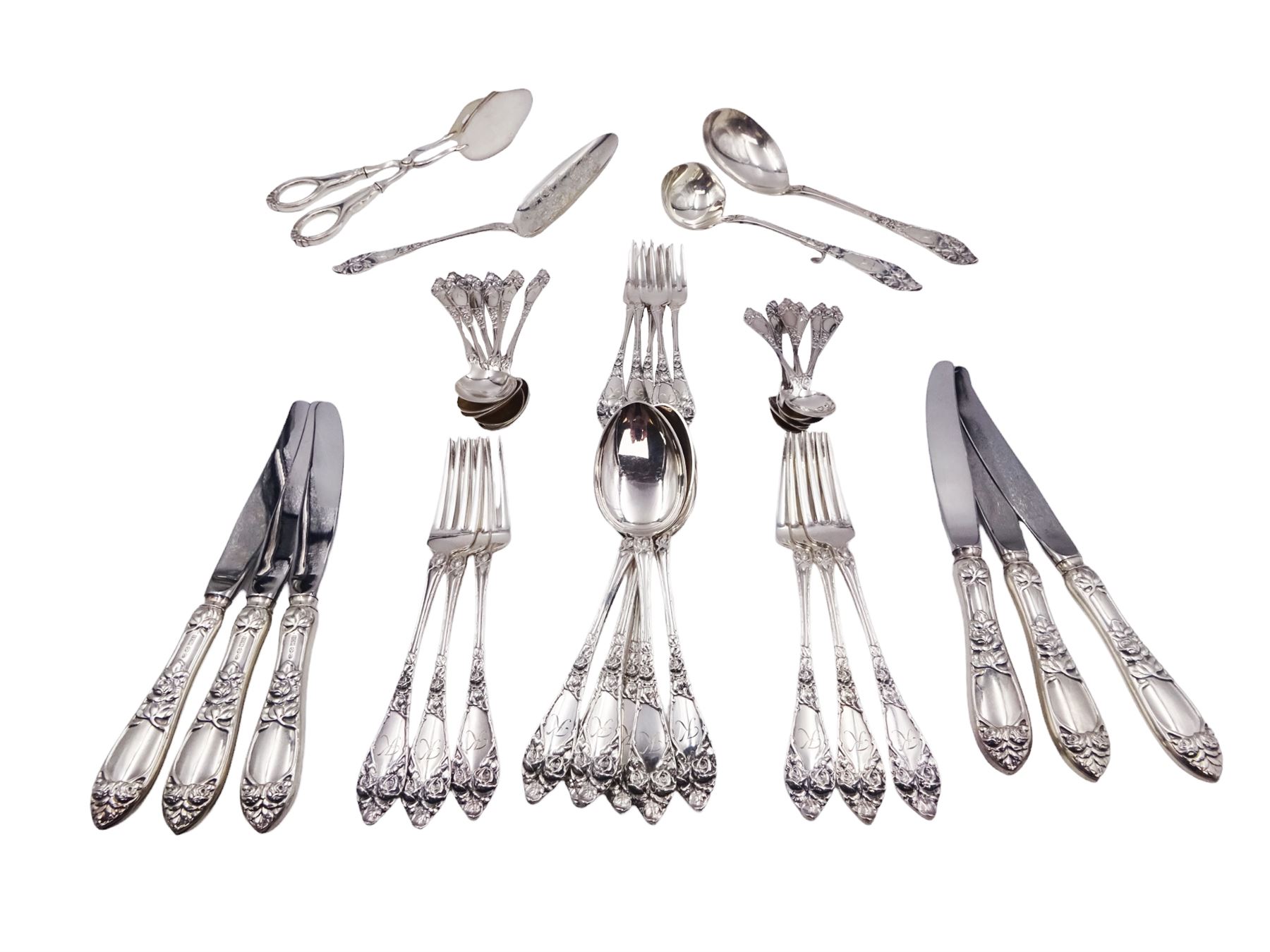 1930s Norwegian silver cutlery for six place settings, comprising table spoons, table forks and silver handled table knives, cake forks, tea spoons and demitasse spoons, one cake slice, serving spoon, sauce ladle and a pair of silver handled servers, all embossed with rose decoration and engraved with initial K to terminal and 10/9 1932 verso, stamped NM 830s