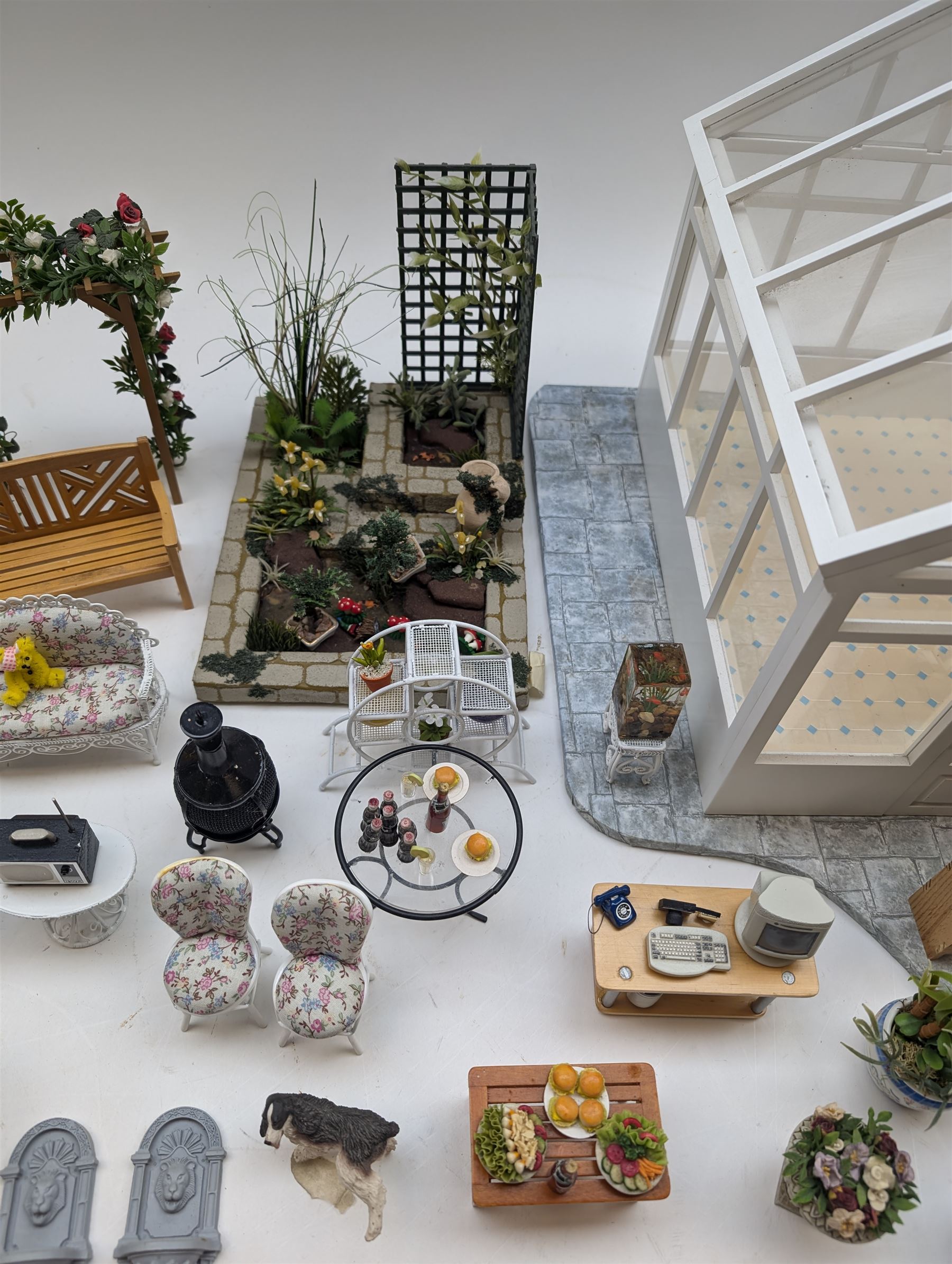 1:12 scale dolls house conservatory and garden accessories, including white wooden glazed conservatory on a stone effect base, black and white metal garden seating, barbecue, plant shelves, parasol, barbeque accessories, large planters, rabbit hutch, animals, chimenea, etc