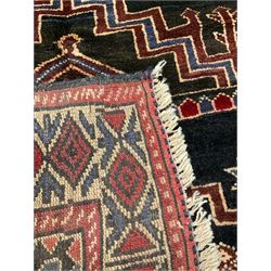 Baluchi dark indigo and crimson ground rug, decorated with cityscape within geometric border 