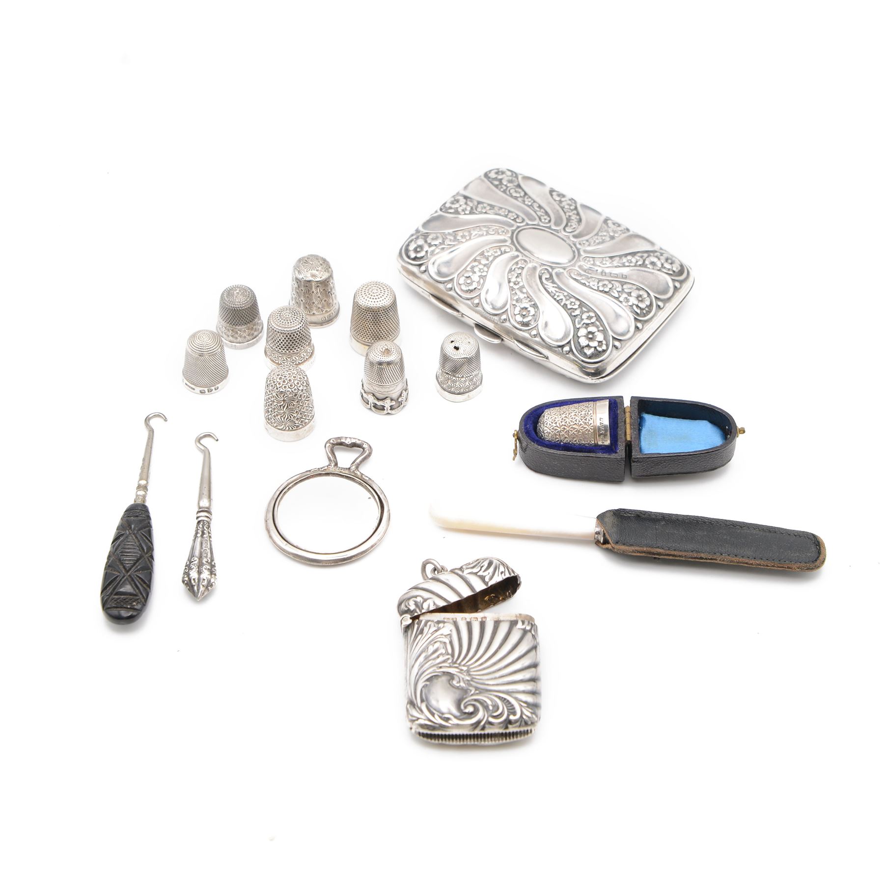 Edwardian silver cigarette case, embossed with floral decoration, hallmarked George Frank Bickerton, Birmingham 1901, together with a silver vesta case, six silver thimbles and three plated thimbles, miniature silver mounted mirror, mother of pearl handled silver fruit knife, and two button hooks