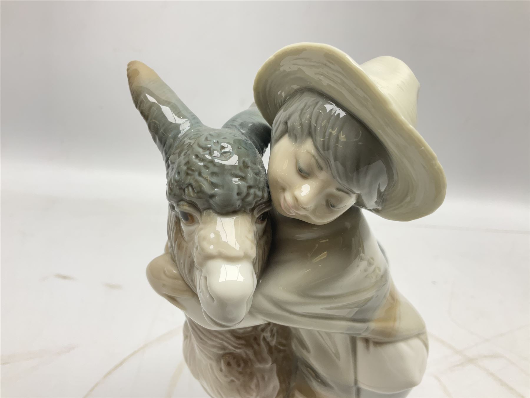 Seven Lladro figures, comprising Playful Puppy no 9135, Platero and Marcelino/Boy Hugging Donkey no 1181, Mini Seal Family no 5318, Attentive Polar Bear no 1207, Seated Polar Bear no1209, Eskimo Boy with Pet no 5238 and Girl with Geese no 1035, together with Nao goose