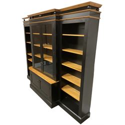 Contemporary polished pine and black finish break-front bookcase, projecting cornice over globular mounts, central cabinet enclosed by two glazed doors over double panelled cupboard, flanked by adjustable shelves, on plinth base