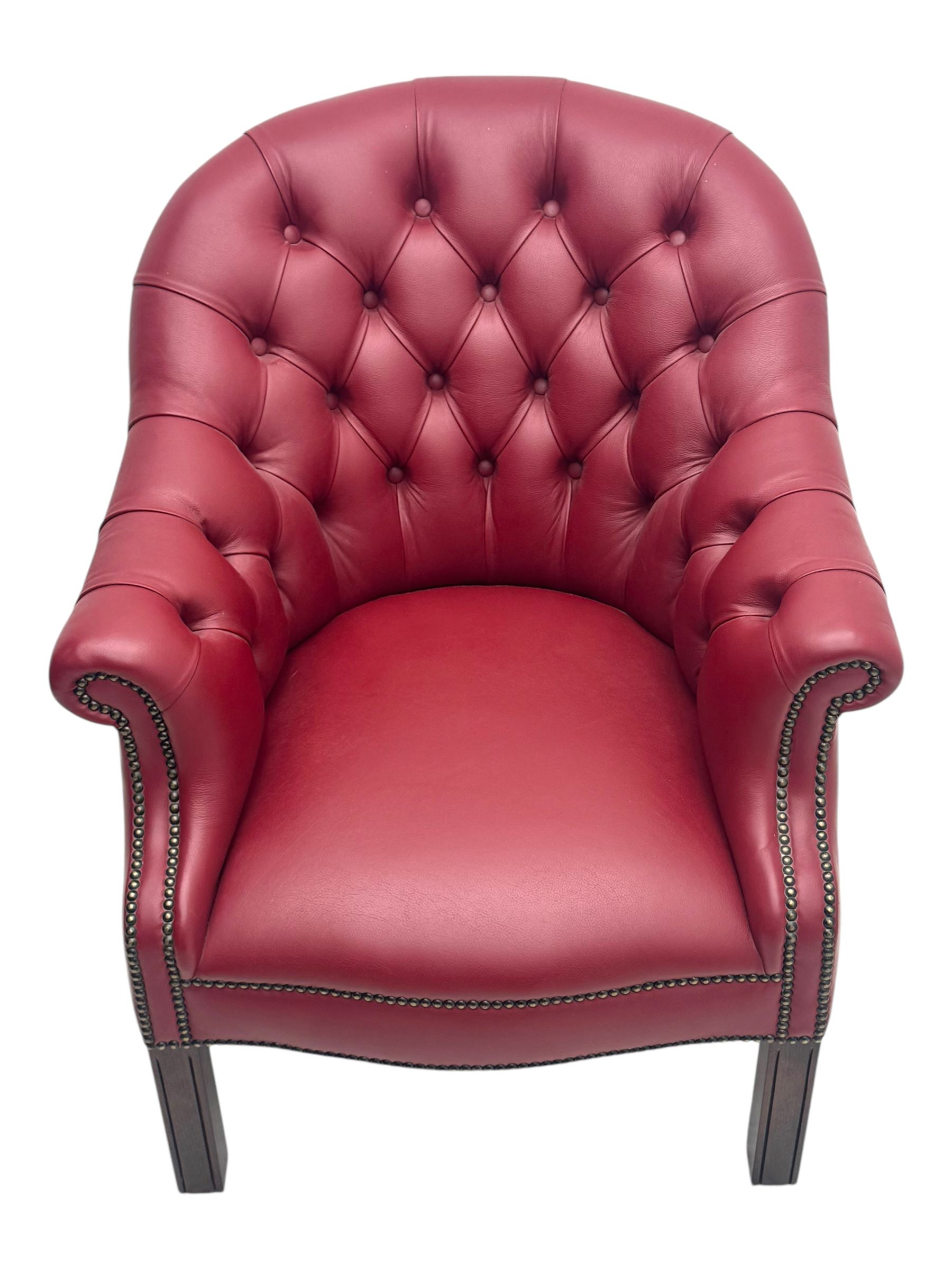 Kingsgate - contemporary 'Devon' bucket armchair, upholstered in red leather with buttoned backrest, rolled arms and brass stud detailing, raised on four dark wood supports with vertical carving