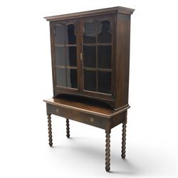 Early 20th century Jacobean Revival dark stained oak dresser, the associated upper section enclosed by twin glazed doors with shaped moulded glazing bars, over separate base fitted with two drawers, raised on bobbin turned legs