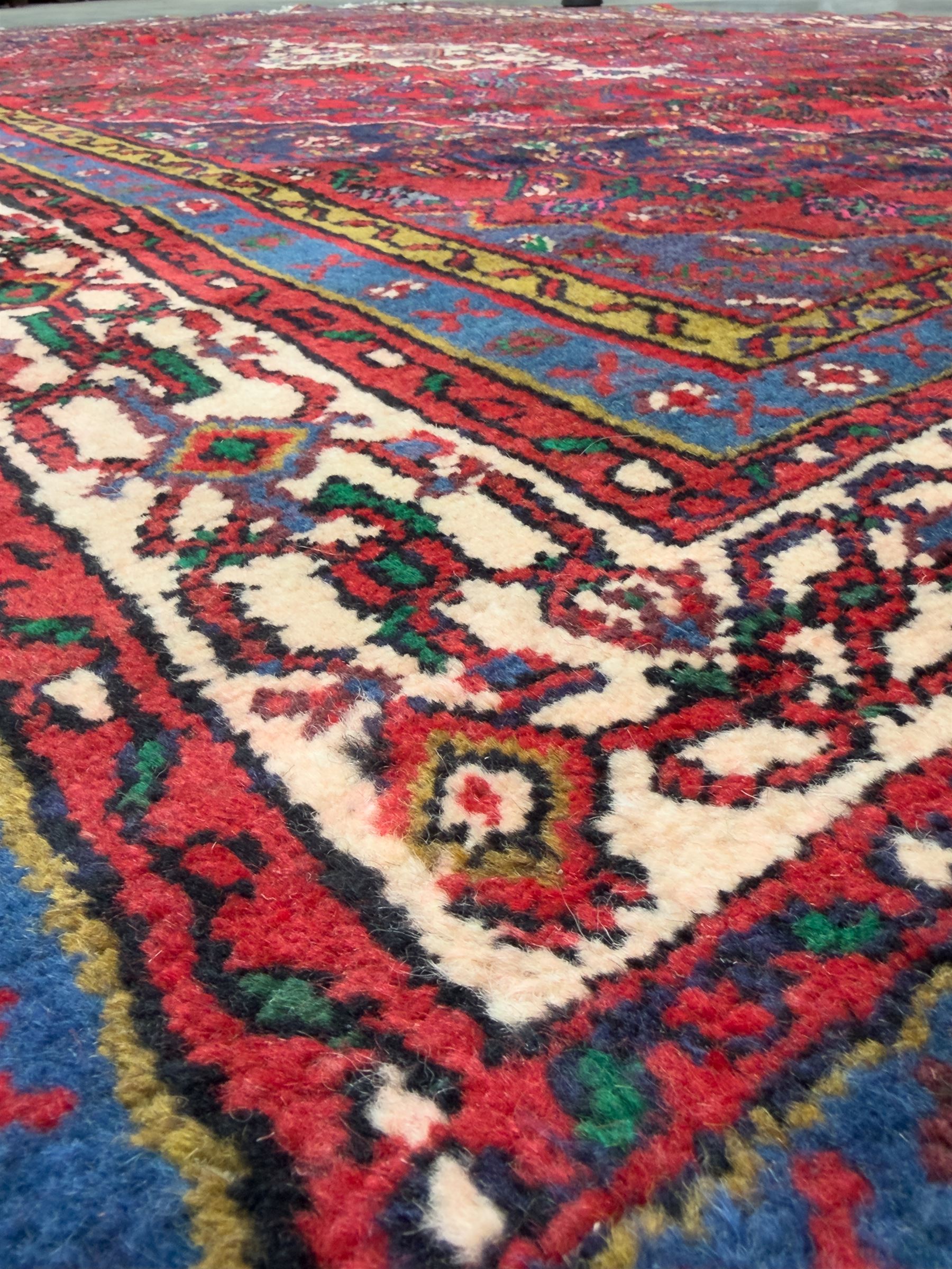 Northwestern Persian Hamadan hand-knotted rug, madder red field with a lozenge medallion enclosing an ivory centrepiece, indigo spandrels within an ivory border of stylized floral motifs between multiple guard borders 