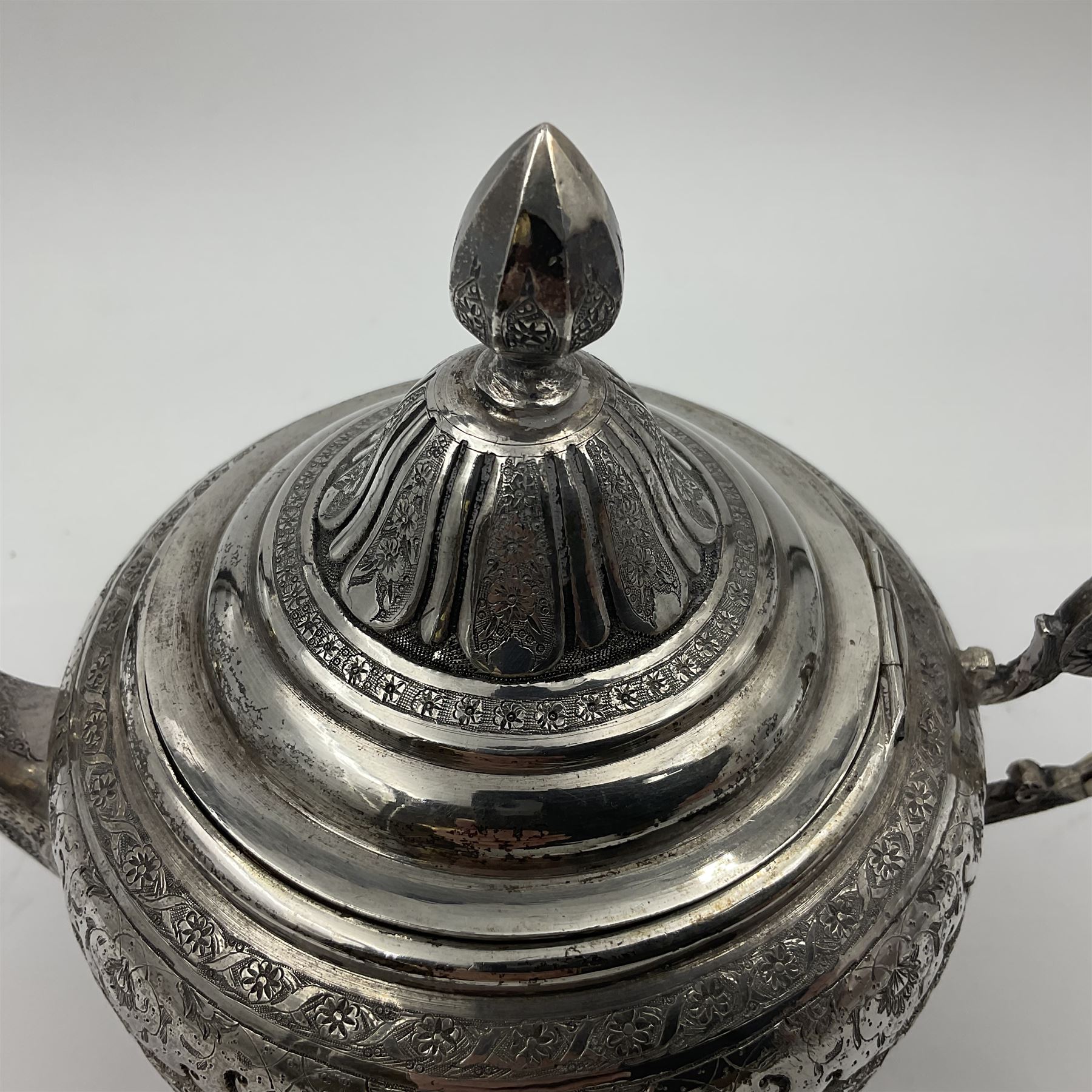Early/mid 20th century Persian silver tea service, comprising circular serving tray, teapot, twin handled sucrier and cover, milk jug, five tea glasses with six silver holders, six tea spoons, and pair of sugar tongs, each profusely chased with foliate arabesque decoration, each bearing marks including 84 for 840 fineness, tray D40cm, teapot H16cm
