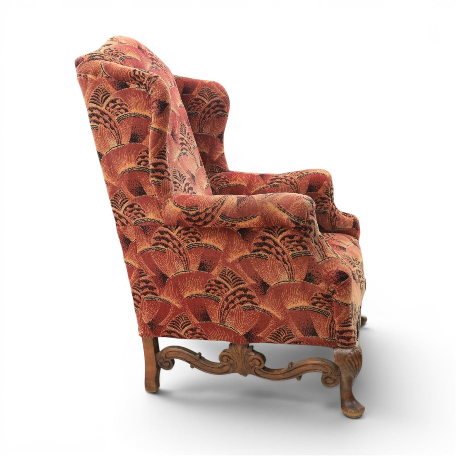 Large upholstered wingback chair, crimson geometric upholstery, carved front apron raised on cabriole supports 