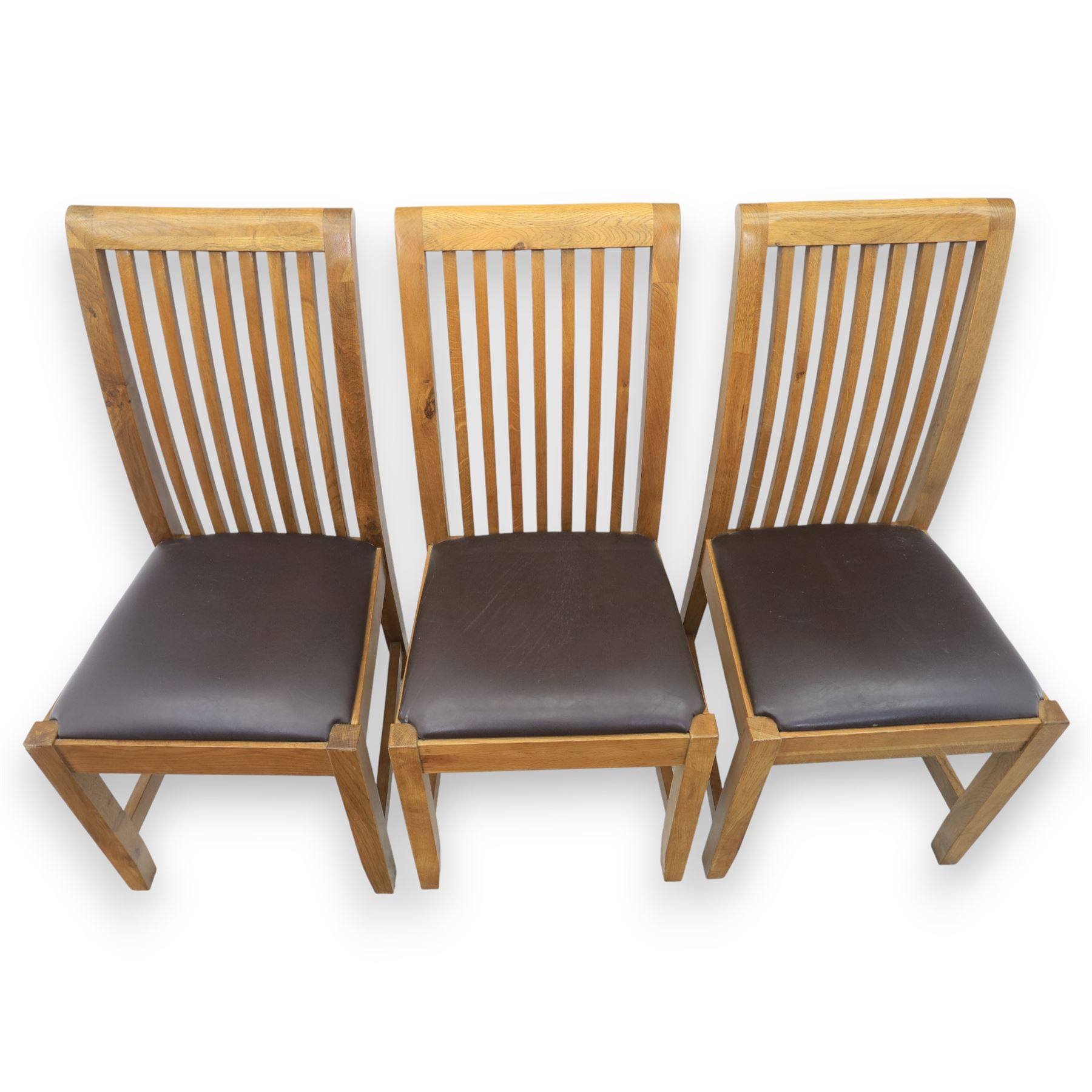 Contemporary oak extending dining table, moulded rectangular top with visible grain and inset extension leaf, pull out extending mechanism, standing on four square legs, accompanied by a set of high slat back chairs with upholstered brown faux leather seats and square tapering supports joined by stretchers