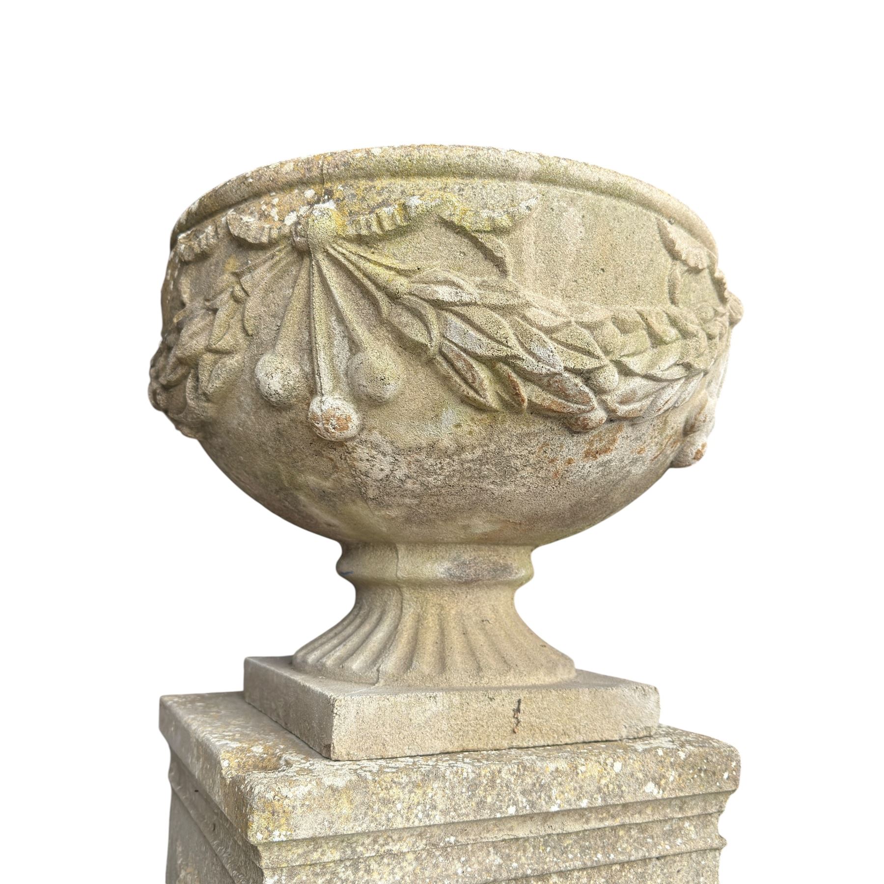 Pair of quality Neoclassical design Haddonstone cast stone garden urns, the globular  body decorated with relief foliate festoons and fruiting motifs, over a fluted socle, the rectangular pedestals with relief foliate wreaths and ribbon garlands