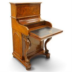 Victorian burr walnut piano-top Davenport, the raised rectangular superstructure with moulded cornice above a panelled fall-front enclosing drawers, the curved hinged writing slope opening to reveal a fitted interior above a sliding tooled leather writing surface, flanked by carved foliate scroll supports, the right side fitted with four drawers behind an arched panelled cupboard door with brass inset campaign-style handles, on a shaped plinth base and bun feet
