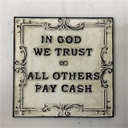 Cast iron 'In God we Trust' sign with black writing on a white ground, H15cm