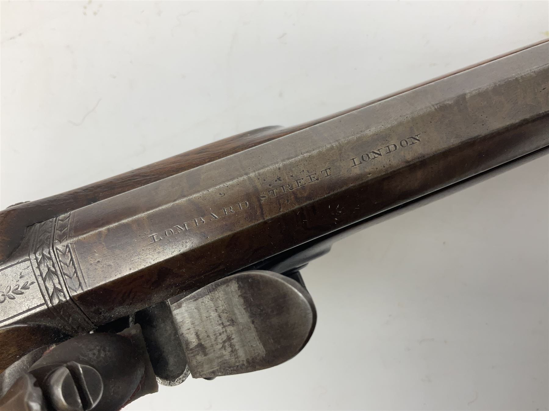 Early 19th century flintlock 16-bore overcoat/duelling pistol by William Bond Lombard Street London, the 23cm octagonal brown stub twist damascus barrel with small foresight, two barrel pins and ram rod under, inscribed Lombard Street London to the top and W. Bond to the action, full walnut stock with lightly engraved steel furniture, pineapple finial and escutcheon, half cock facility L39cm; loose mounted on later mahogany display stand with trade label