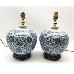 A pair of blue and white table lamps, of bulbous form decorated with foliate design in an Oriental style, with accompanying white fabric shades, overall H49cm. 