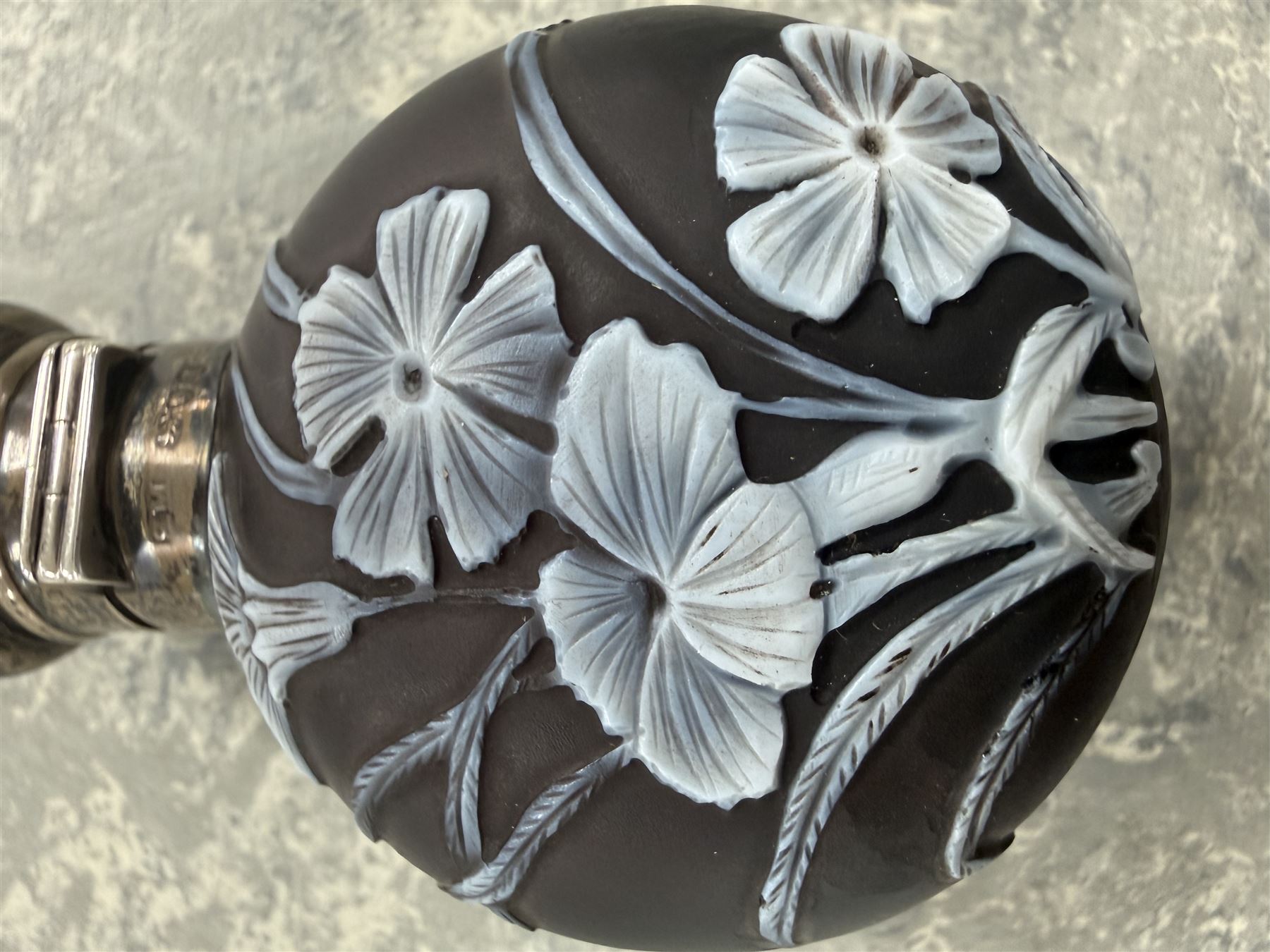 Victorian Thomas Webb silver mounted cameo glass scent bottle, hallmarked Sampson Mordan and Co, London 1884, the cameo glass body of circular form, decorated with white flowers and foliage in high relief upon a black ground, the hinged cover opening to reveal the original stopper, H6cm 