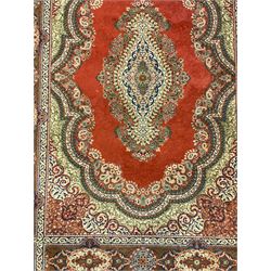 Persian design crimson ground rug, overall floral design, the field decorated with shaped spandrels and central medallion, the border with rectangular panelled decorated with floral motifs 