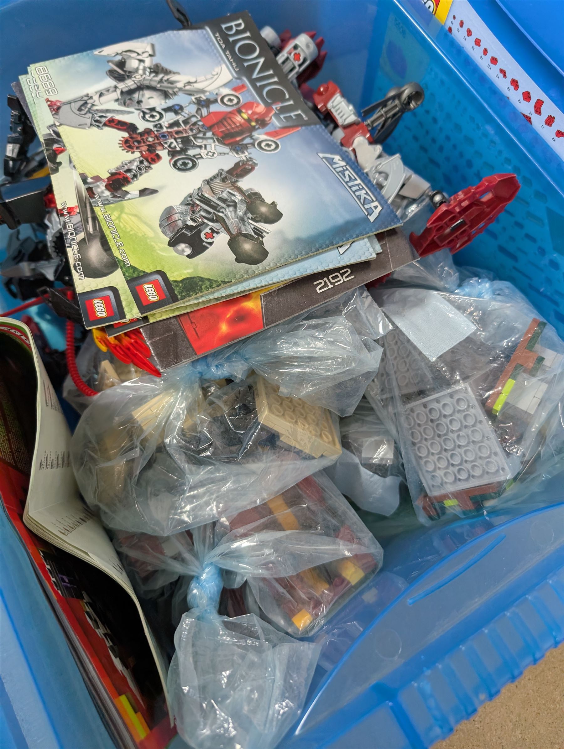 Collection of Lego, including built Bionicles Mistika models with instructions, loose Lego pieces, Lego Beatles Abbey Road canvas print and a Lego head storage box