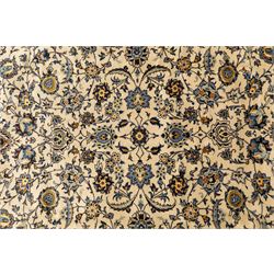 Central Persian Kashan hand-knotted rug, ivory field intricately decorated with an all-over design of scrolling vines, palmettes, and stylized lotus motifs in shades of soft blue, pale gold, and indigo within floral borders