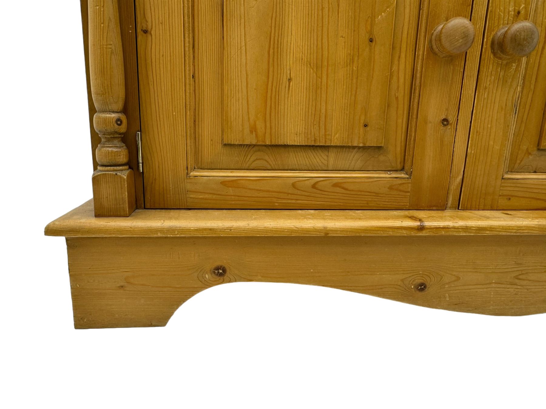 Early 20th century pine kitchen dresser, featuring a hutch with arched top over three open shelves, the base with five drawers over three cupboard doors, turned column supports flanking the doors, scalloped apron base with bracket feet