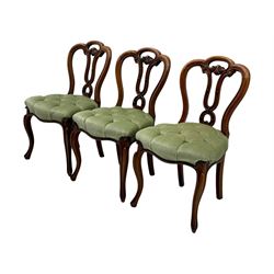 Set of six carved Victorian walnut balloon back dining chairs, button upholstered in green velvet fabric, back with foliate carved decoration supported on scroll form legs 