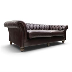 Thomas Lloyd - traditional shape Chesterfield two seater settee with rolled back and arms, upholstered in buttoned deep oxblood leather with loose seat cushions, raised on turned feet