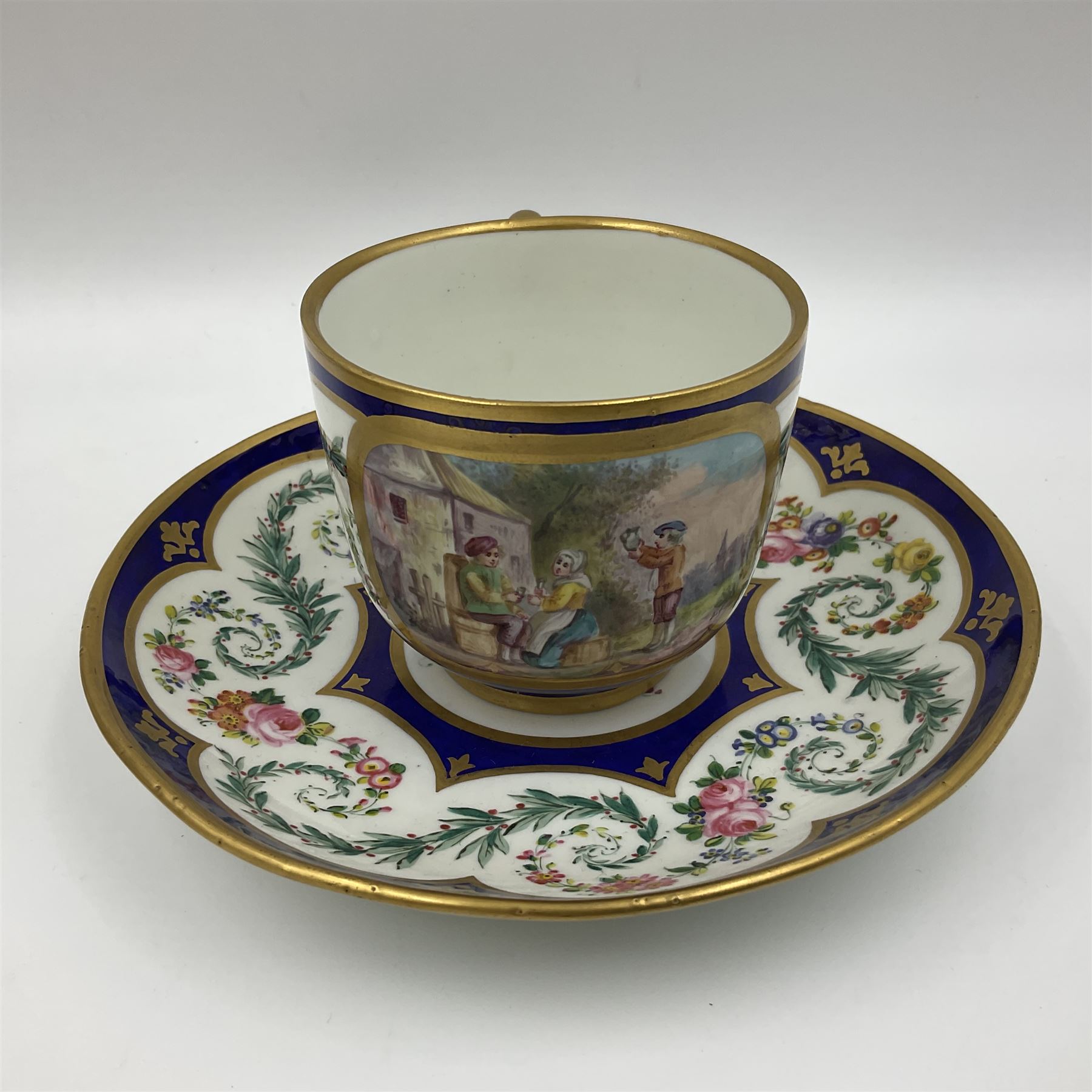 19th Sèvres style porcelain cup and saucer, the cup painted with a figural scene, against a scalloped border of scrolling floral swags on a blue ground, together with a Sèvres soft paste porcelain coffee can and saucer, painted with panels of exotic birds, roses and a border of cornflowers, LL monogram enclosing date letters H above painters mark, coffee can H6.5cm, saucer D13.5cm (2)