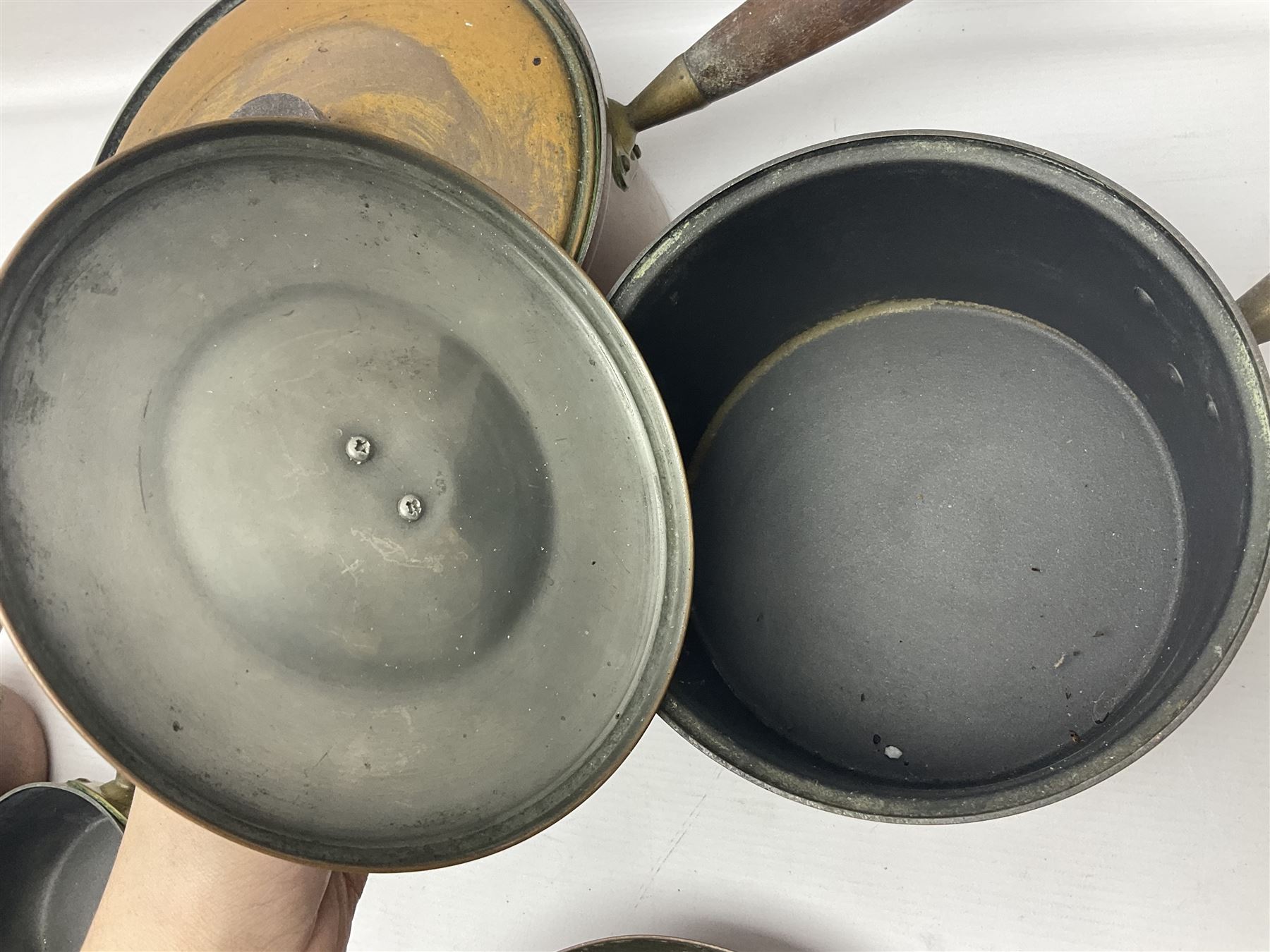 Four Victorian copper moulds, together with a graduating set of copper pans with wooden handles and finials to covers, largest pan 