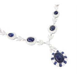 18ct white gold sapphire and diamond milgrain set necklace, oval cabochon cut sapphire surrounded by eight round brilliant cut diamonds and eight French cut sapphires, suspending from a diamond set leaf pendant, single round brilliant cut diamond and a larger old cut diamond, the chain set with six graduating cabochon cut sapphires, each surrounded by diamonds and spaced by a single diamond and a diamond set leaf, to a belcher link chain necklace, hallmarked, total sapphire weight approx 27.00 carat, total diamond weight approx 7.50 carat