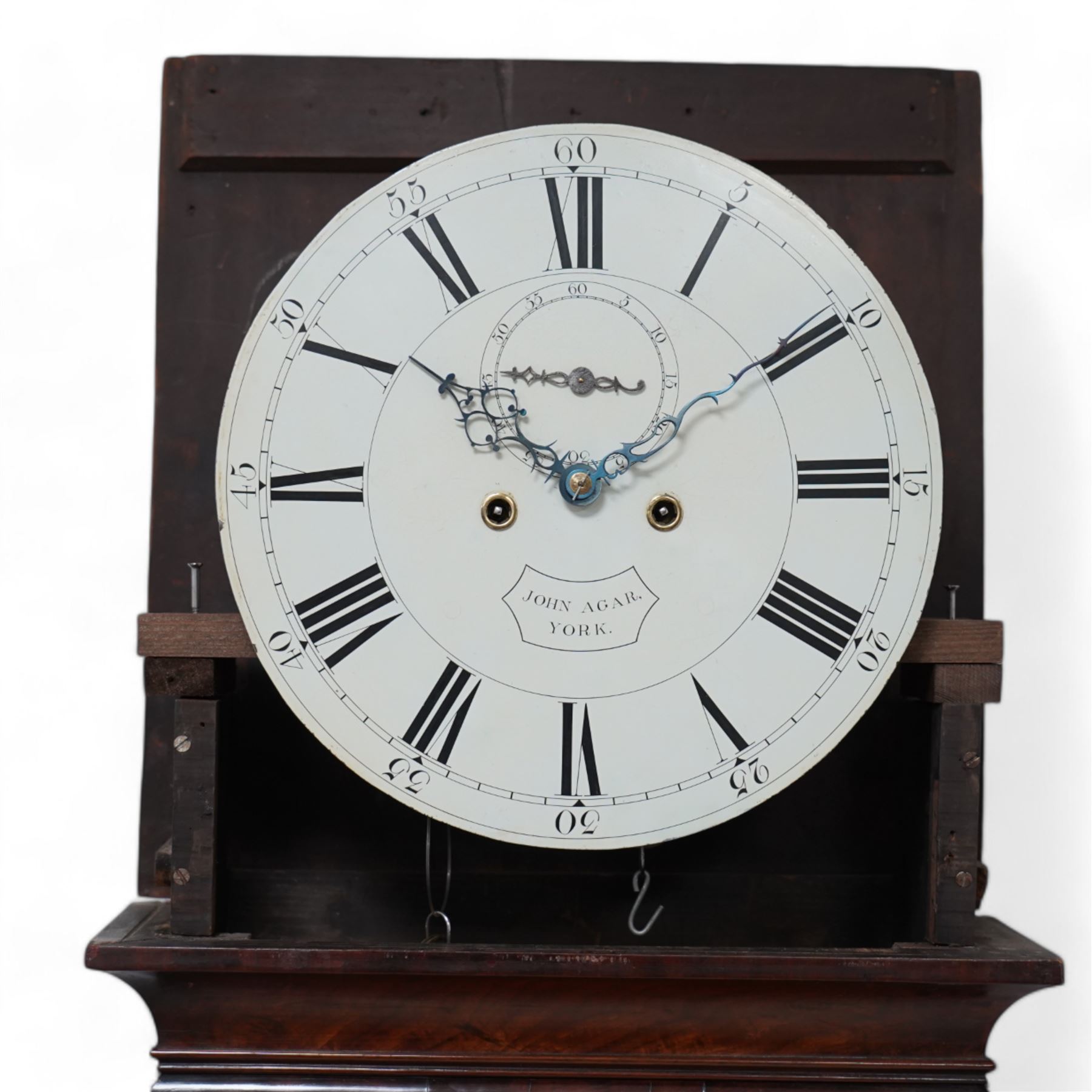 John Agar of York - Early 19th century 8-day mahogany longcase clock c1810, with a flat topped pediment and ogee cornice beneath, square hood door flanked by slender turned pillars with wooden capitals, glass side panels to the hood sides and a glazed circular dial aperture, trunk with conforming recessed pillars and a long door with a shallow curved top, square plinth with a moulded front panel and flat base on shallow feet, painted dial with makers name, Roman numerals, five minute Arabic's and minute track, matching steel hands and seconds dial, with a four pillar rack striking movement striking the hours on a bell. With weights, pendulum and key.
The Agar family were a large and prodigious family of 18th and 19th century York clockmakers working in the city and towns in the surrounding locality.