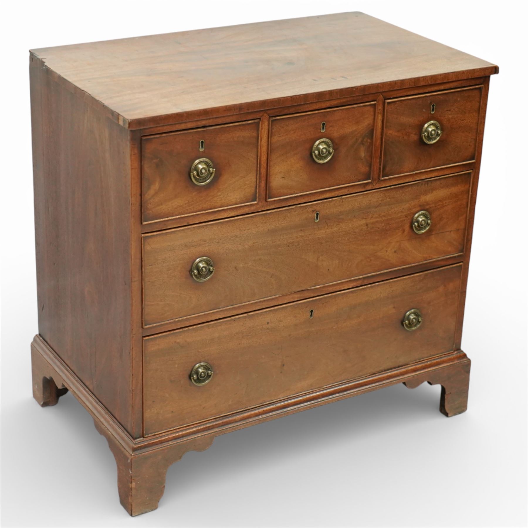 Small 19th century mahogany chest of drawers, rectangular top with moulded edge over three short and two long drawers, the drawers fitted with brass ring handles and key escutcheons, raised on shaped bracket feet