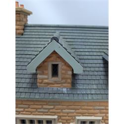 1:24 scale stone effect three-storey cottage dolls house, with green arched door and lattice effect windows, decorated to the interior with wooden floors, wired lighting and fire places, H45cm, W57cm, D26cm