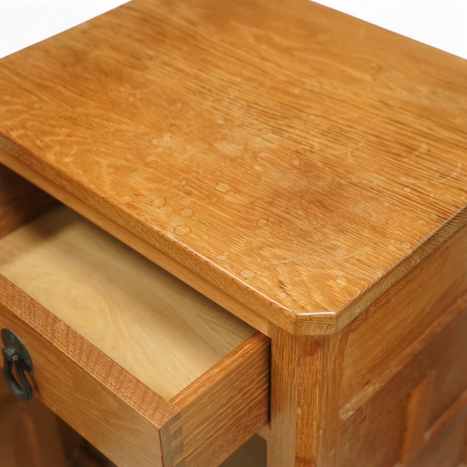 Beaverman - pair of oak bedside cabinets, each with plain rectangular top over single drawer and cupboard below with fielded panels and wrought iron hardware, with signature carved beaver, by the workshop of Colin Almack, Thirsk